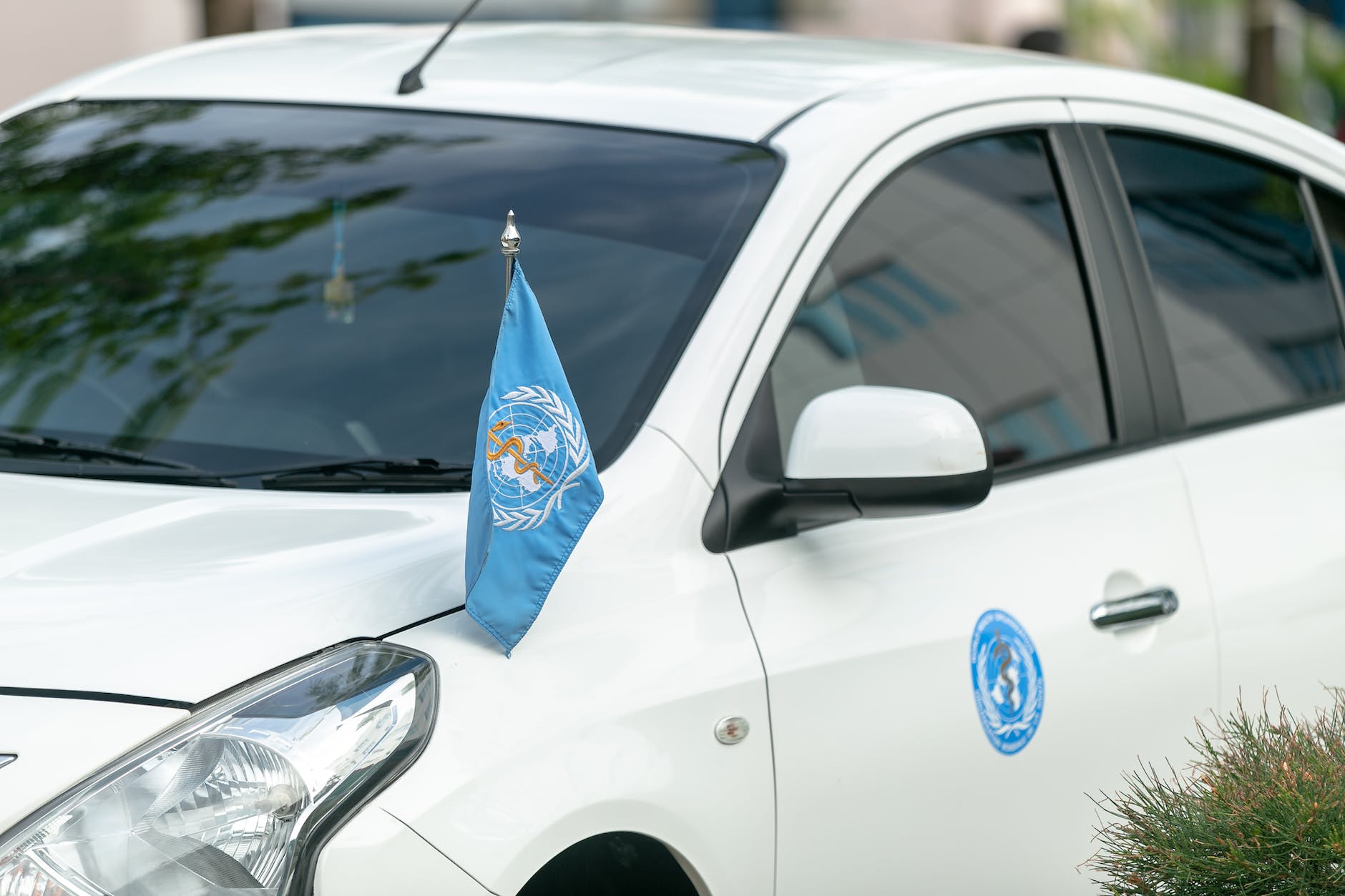 modern white car with world health organization flag and sticker